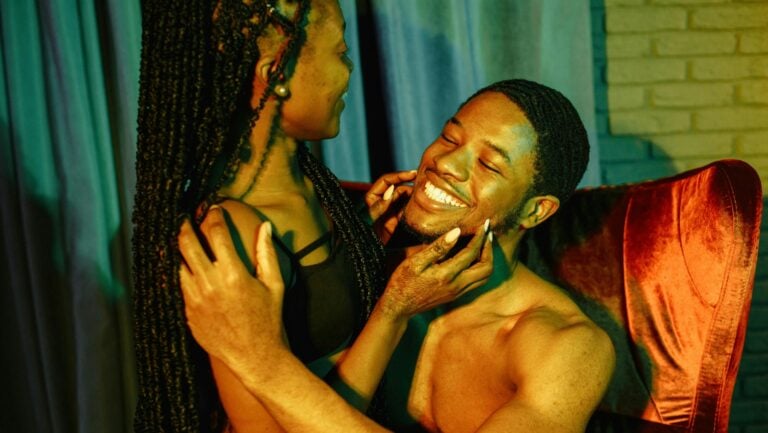 Un couple souriant se fait face, tous deux nus, prêts à explorer les positions du Kamasutra qu'ils préfèrent.