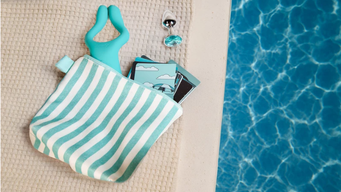 La Summer Box d'Adam et Eve est photographiée sur un serviette claire, à côté d'une piscine d'un bleu profond.