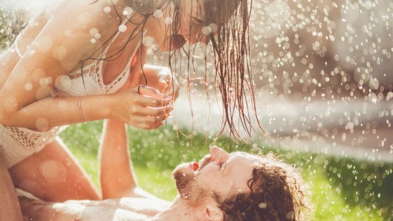 Un couple joue à se chatouiller, allongé sur l'herbe, prêt à faire l'amour à l'extérieur.