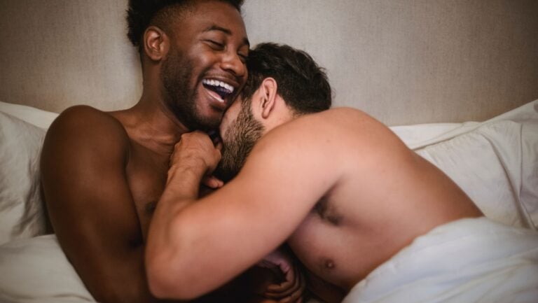 Un couple d'hommes est hilare dans leur lit.