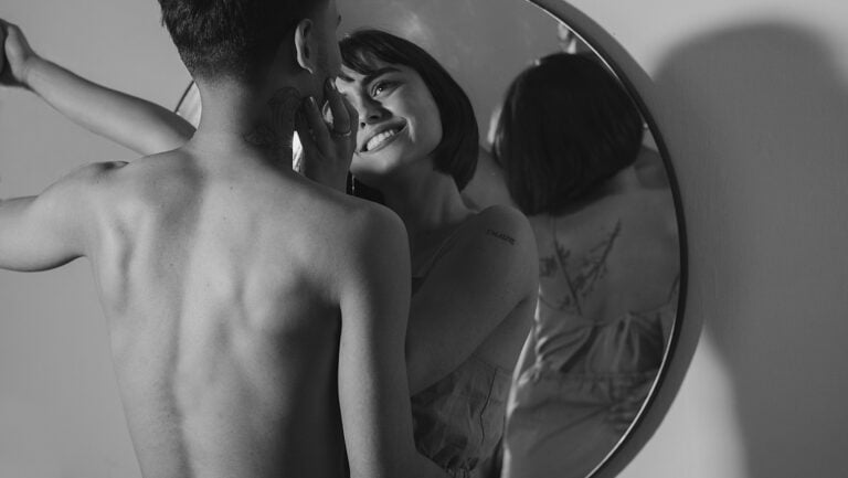 Un couple rieur se dévisage du regard avec intensité, nu et prêt à vivre leur belle histoire érotique.
