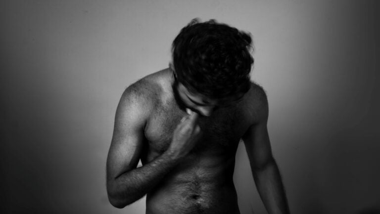 Une homme est torse nu, regardant vers le bas, envie de vivre une histoire érotique avec lui même.