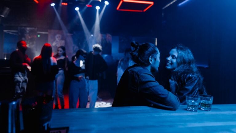 Deux personnes accoudées au bar se regarde avec désir, prêts à initier une histoire érotique et bien chaude.