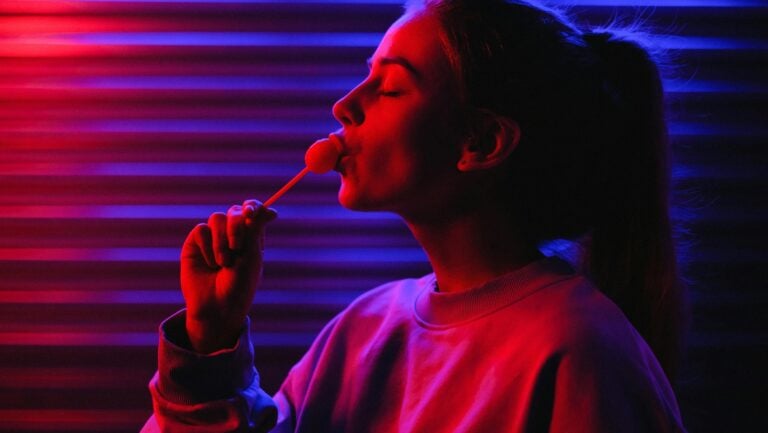Une jeune femme se tient dans la rue, la nuit, une sucette à la bouche. L'ambiance donne le sentiment qu'une histoire érotique est sur le point de se passer.