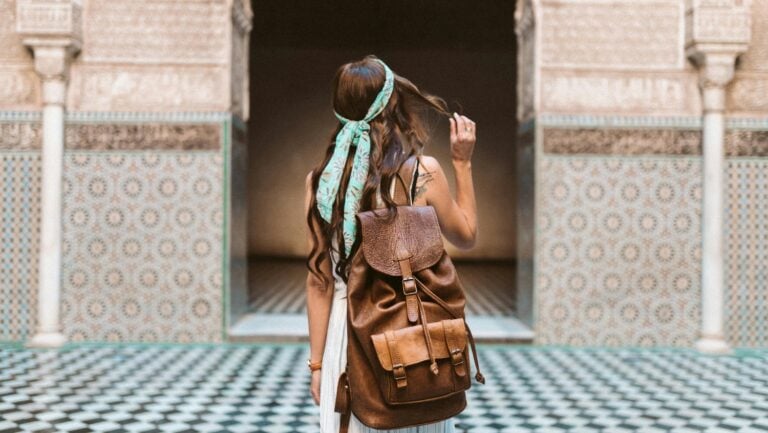 Une jeune femme aux longs cheveux châtains se tient debout devant la porte d'un Riad marocain, prête a entrer dans une folle histoire érotique.