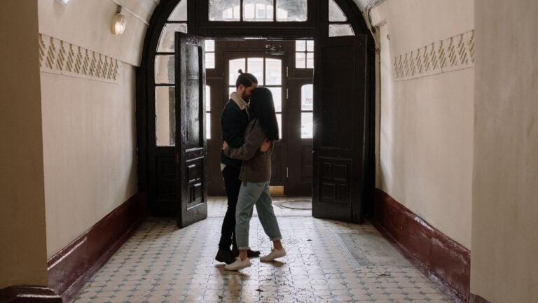 Un couple s'embrasse dans un hall d'entrée éclairé, prêts pour une histoire érotique.