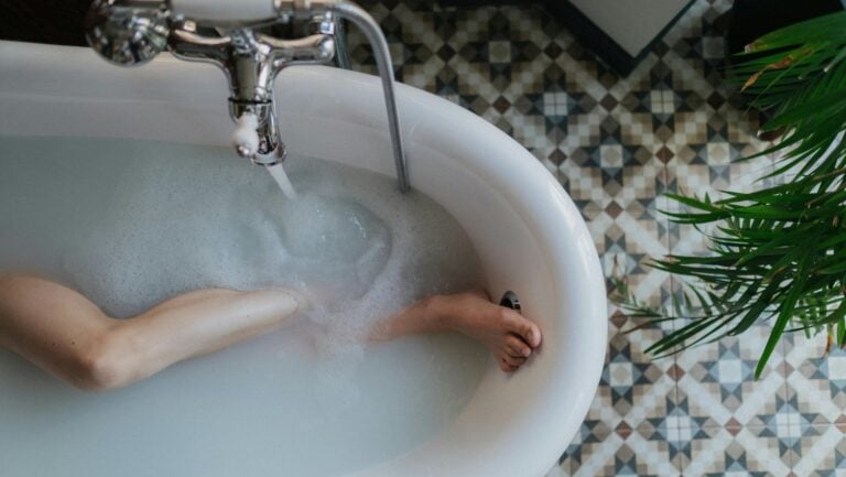Une vue supérieure d'un bain à l'eau laiteuse. Un pied crispé est appuyé contre le bord de la baignoire, indiquant une histoire érotique en cours.