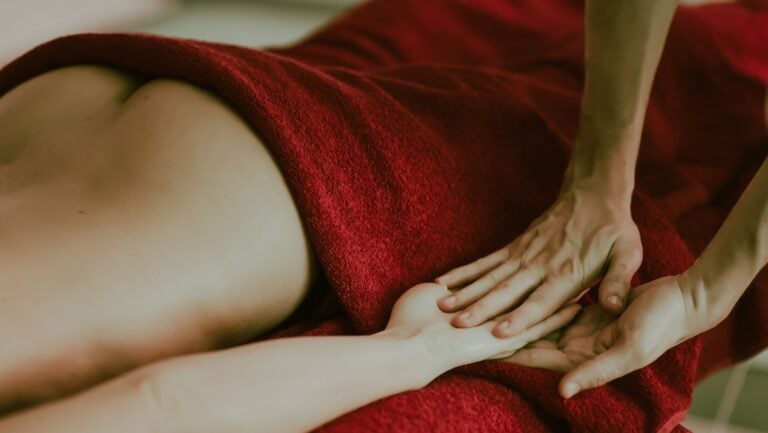 Une personne allongée se laisse masser, les fesses à moitié dénudées, prête à vivre une historie érotique.