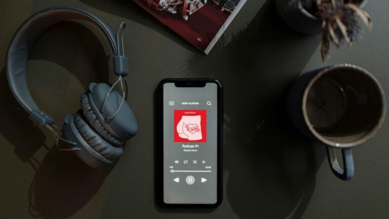 Un téléphone est posé sur un bureau. On peut y voir le logodu podcast sexe et sexy d'Adam et Eve : Qriosité.