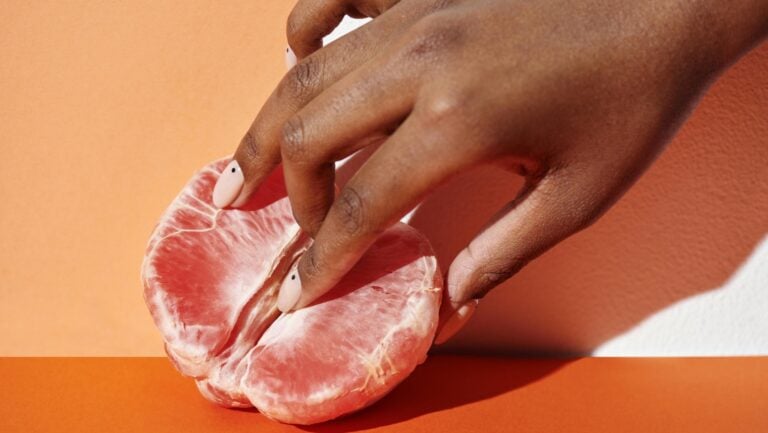 Pour illustrer notre guide d'achat de la gamme Womanizer, une main s'introduit lentement dans un pamplemousse, symbolisant la vulve.